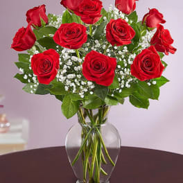Arrangement of red roses with white filler flowers in a clear glass vase