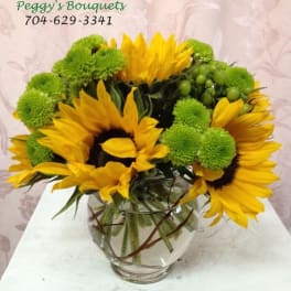 Sunflowers and green pom-pom mums in a glass vase