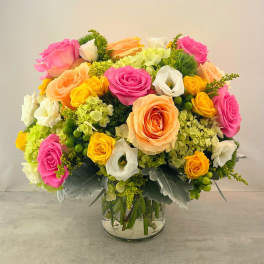 Bouquet of pink, peach, yellow, and white roses in a glass vase