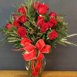 Red roses arranged in a glass vase with a red ribbon bow