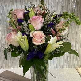 Pink roses and white lilies arranged in a clear glass vase