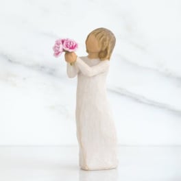 Wooden figurine in a white dress holding pink flowers