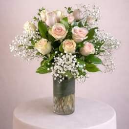 Bouquet of pale pink roses and baby's breath in a glass vase