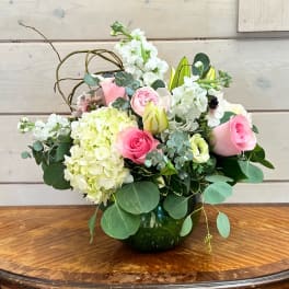 Pink roses and white blooms arranged in a glass vase