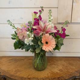 Mixed pink and peach flowers arranged in a glass vase