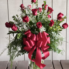 Red roses in a clear vase with a large red ribbon bow