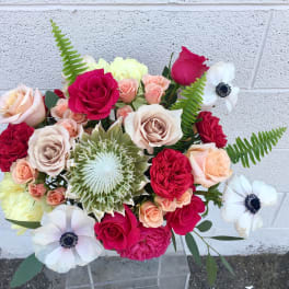 Mixed bouquet of roses and white anemones in a clear vase
