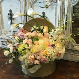 Pastel floral arrangement with white calla lilies and roses in a round box