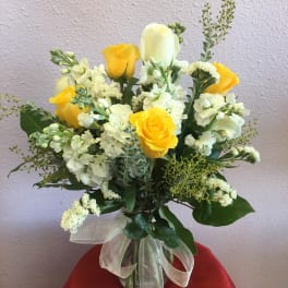 Yellow and white rose bouquet in a glass vase with a ribbon