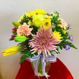 Mixed bouquet in a glass vase with pink, yellow, and purple flowers