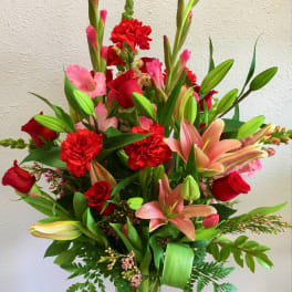 Tall bouquet of red and pink flowers in a clear glass vase