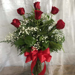 Red roses in a glass vase with baby's breath and a red ribbon