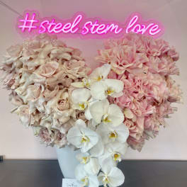 Large pink and ivory floral arrangement in a white vase with orchids