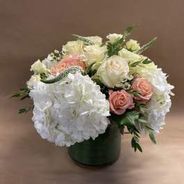 Bouquet of white hydrangeas and blush roses in a green vase