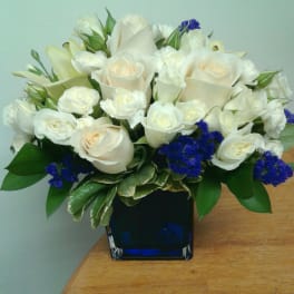 White roses and calla lilies arranged in a blue glass vase
