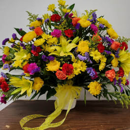 Large mixed bouquet with yellow lilies, roses, and daisies in a white vase