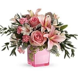 Pink roses and lilies arranged in a pink glass vase