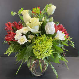 Mixed bouquet of white roses, red alstroemeria, and green hydrangea in a glass vase.