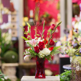 Red roses and white lilies in a red glass vase