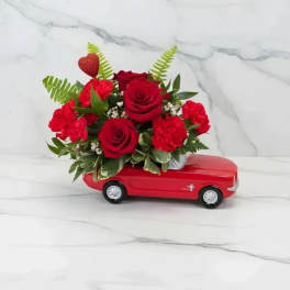 Red rose and carnation arrangement on a red toy car