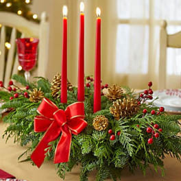 Holiday centerpiece with red candles, pinecones, and a red bow