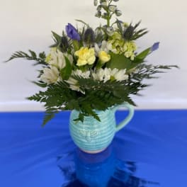 Blue and white flower arrangement in a light blue ceramic pitcher