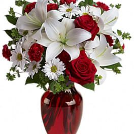 Red roses and white lilies in a red glass vase