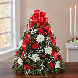 Christmas tree-shaped floral arrangement with red ribbon and white flowers