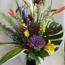 Tall tropical bouquet with calla lilies, orchids, and bird-of-paradise in a dark vase