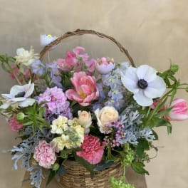 Mixed pastel flowers arranged in a wicker basket
