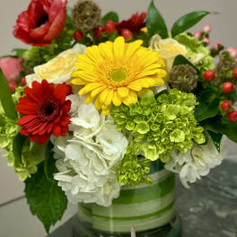 Mixed bouquet with gerbera daisies, hydrangeas, and roses in a glass vase