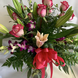 Bouquet of pink roses, lilies, and purple orchids in a glass vase
