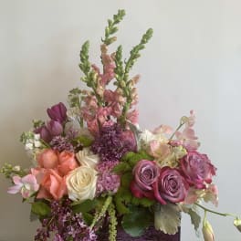 Mixed bouquet of pink, peach, and white flowers in a rectangular container