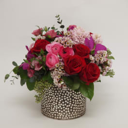 Red and pink roses arranged in a patterned vase