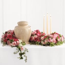 Pink rose funeral urn surround with three taper candles