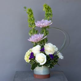 White roses and lavender chrysanthemums in a ceramic vase