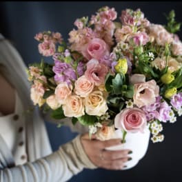Woman holding a pastel bouquet in a white vase
