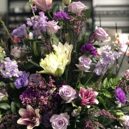 Tall mixed bouquet of pink, purple, and white flowers in a black vase