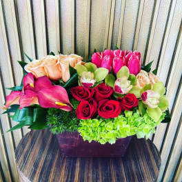 Mixed bouquet with roses, tulips, orchids, and calla lilies in a rectangular vase