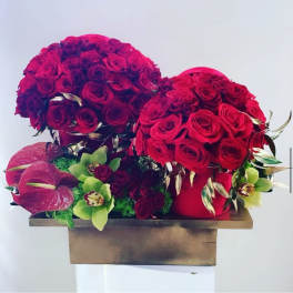Two red rose arrangements with pink anthuriums in a wooden box
