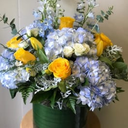 Bouquet of blue hydrangeas and yellow roses in a green vase
