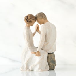 Wooden figurine of a seated couple touching foreheads and hands