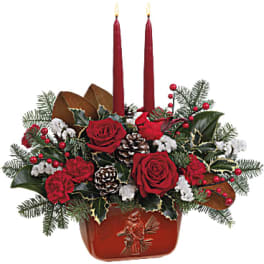 Red roses and carnations in a red container with two lit candles