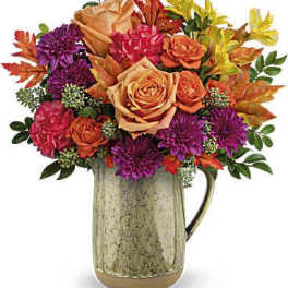 Bouquet of orange and purple flowers in a ceramic pitcher
