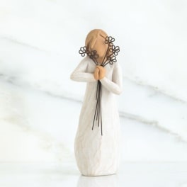 Small figurine in a white dress holding flower stems