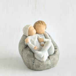 Small figurine of two children sitting together on a gray stone-like base