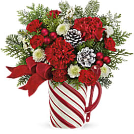 Red carnations and white blooms in a striped mug with ribbon