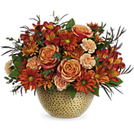 Orange and peach mixed flower arrangement in a patterned vase