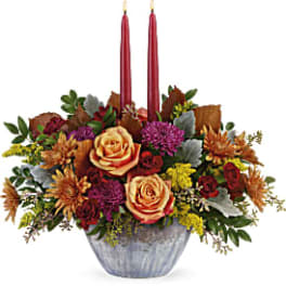 Autumn floral centerpiece in a silver bowl with two red taper candles