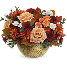 Autumn bouquet of cream roses and orange chrysanthemums in a patterned vase